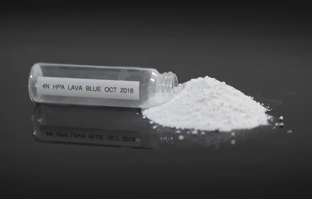 A vial labelled "4N HPA Lava Blue Oct 2018" tipped over beside a small pile of white high-purity alumina powder