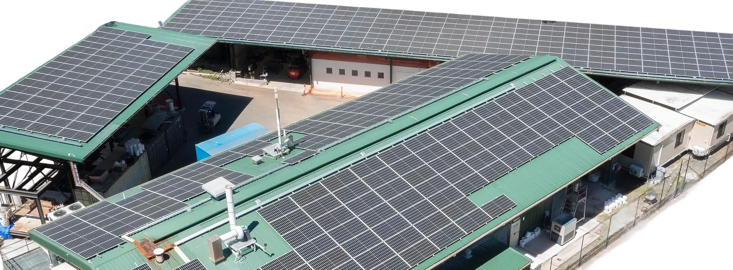 Aerial view of the PRiSM facility, its roofs covered in solar panels, with process tanks and a battery container alongside